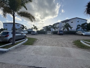 A parking area with multiple cars, palm trees, and a building in the background. - Luxurious Beach Front Villa Pool-Gym-AC Sleeps 5! (Turtle Bay)