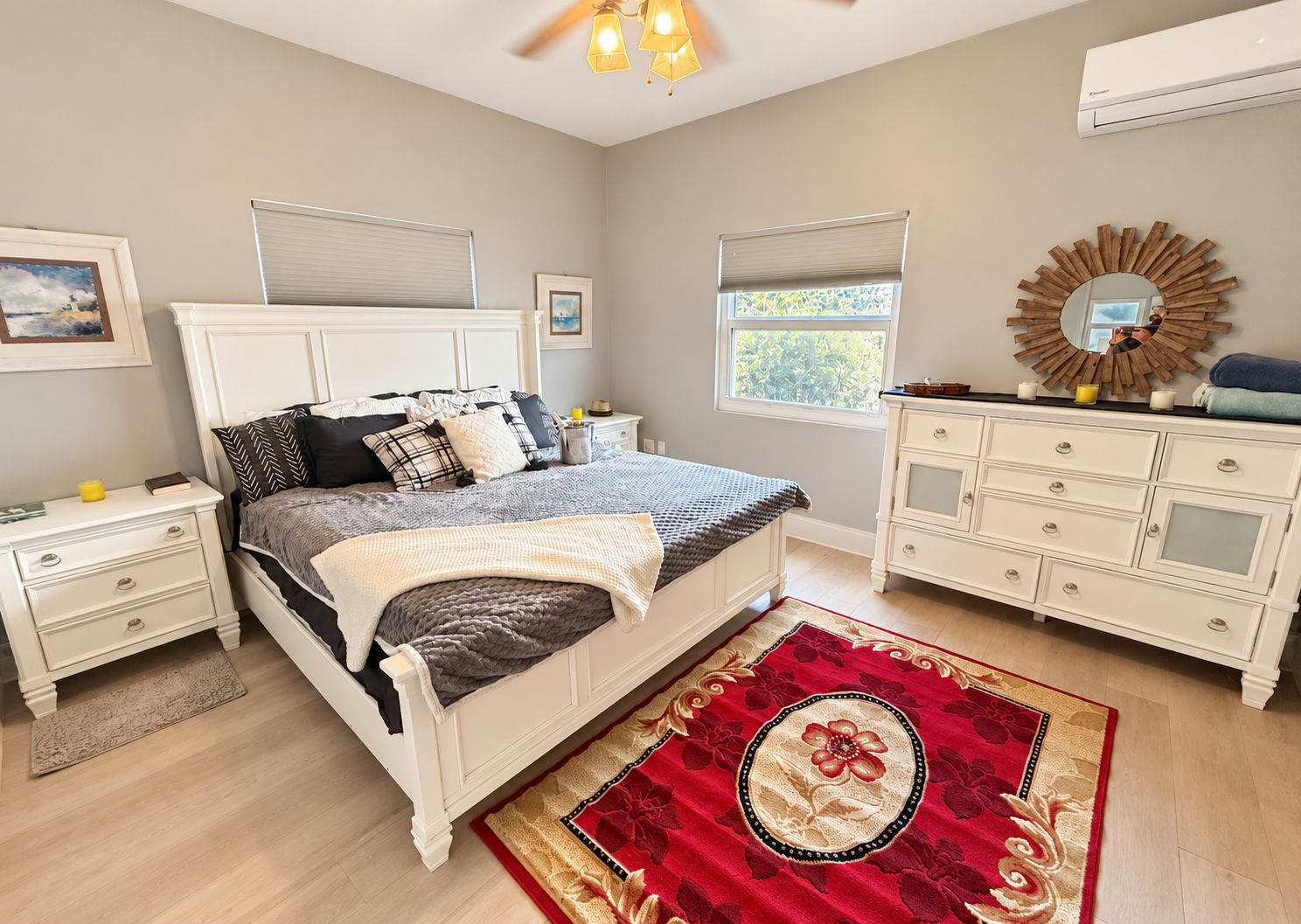 A bedroom with a bed, nightstands, a dresser, a mirror, and a window.