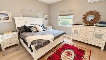 A bedroom with a bed, nightstands, a dresser, a mirror, and a window.