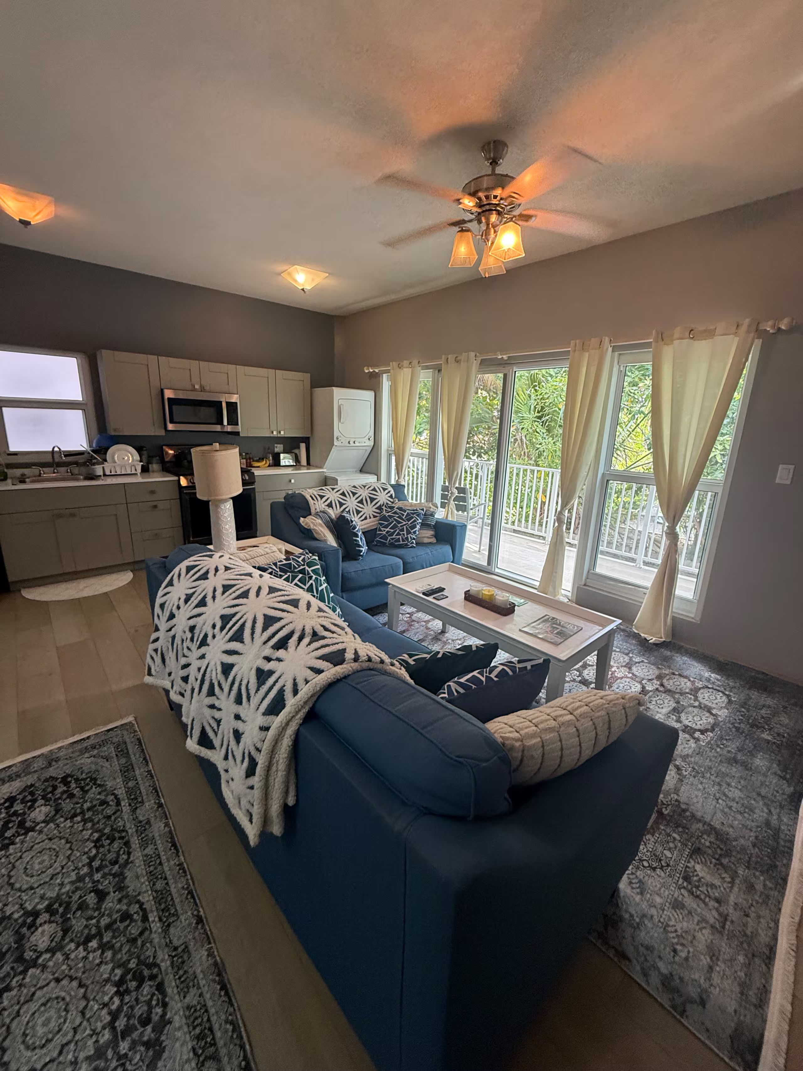 A modern living room with a blue sofa, a coffee table, and a ceiling fan.