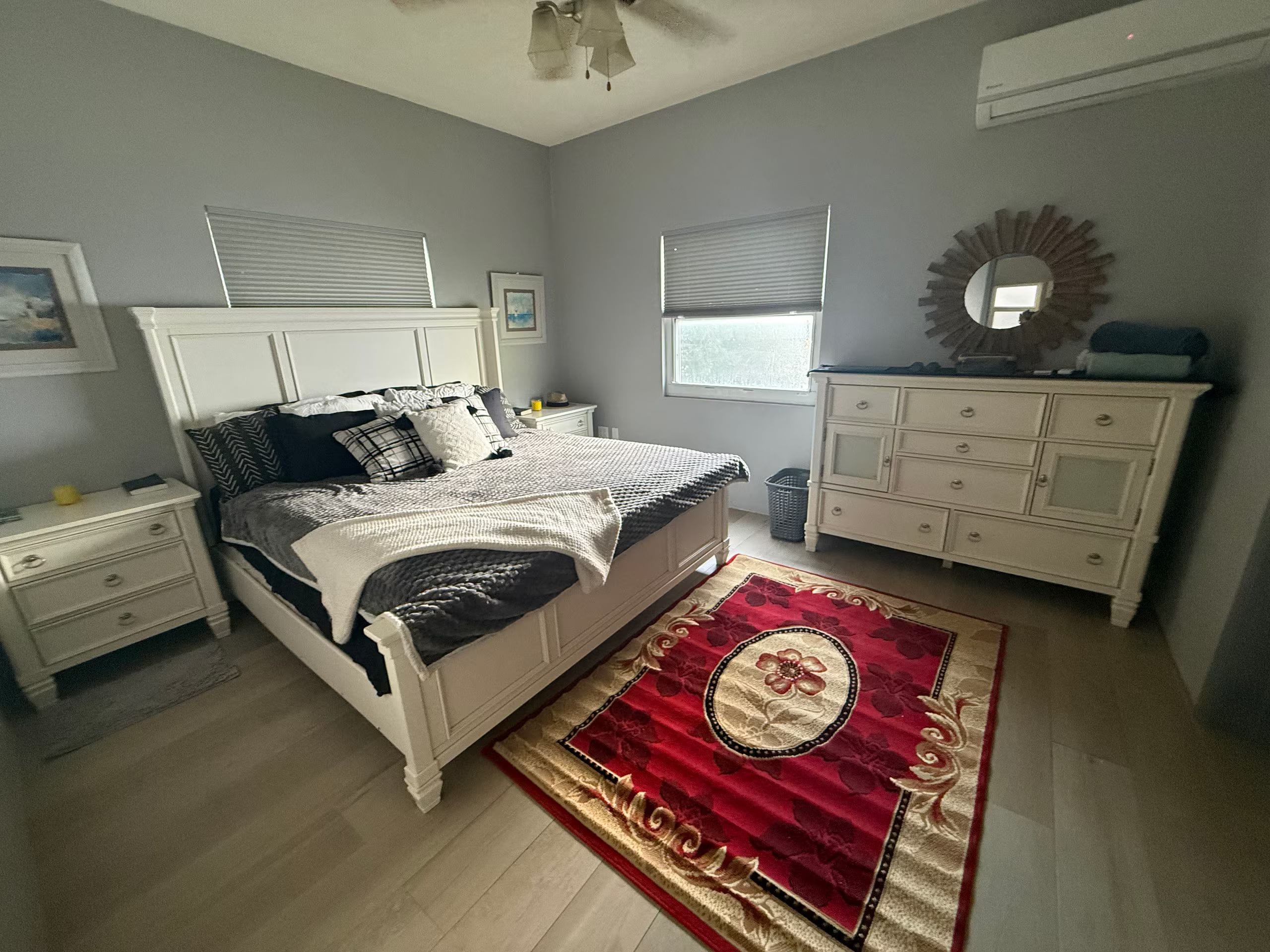 A bedroom with a bed, bedside tables, a dresser, a mirror, and a window.