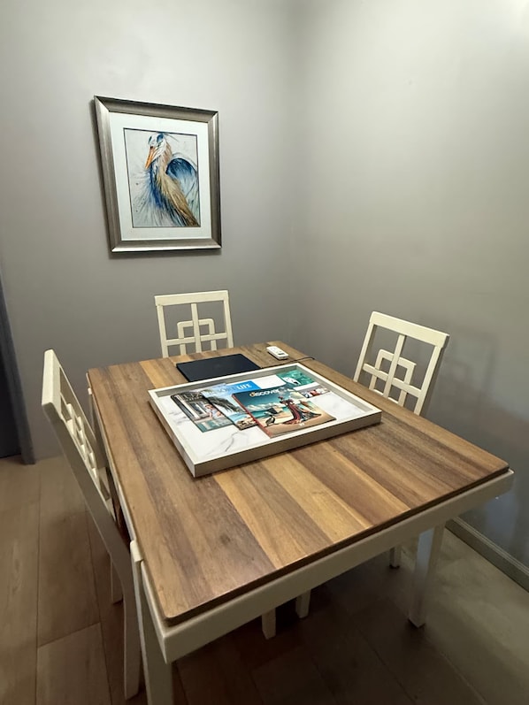 A dining table with a framed artwork above it, surrounded by white chairs. - Luxurious Beach Front Villa Pool-Gym-AC Sleeps 5! (Turtle Bay)