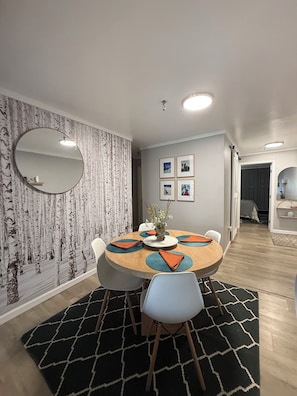 A dining area with a round table, chairs, a mirror, and framed pictures on the wall. - Your Perfect Snowshoe  Getaway make most of the mountains in this stylish condo! (Snowshoe)