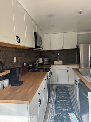Una cocina moderna con armarios blancos, microondas integrado, cocina a gas y refrigerador de acero inoxidable.
