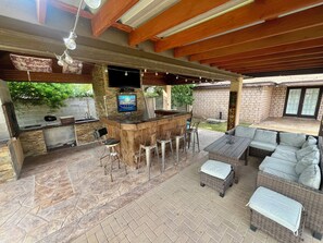 Eine Terrassengaststätte mit Barbereich, Sitzgelegenheiten und einem Fernsehbildschirm, der 'FOOTBALL' zeigt.