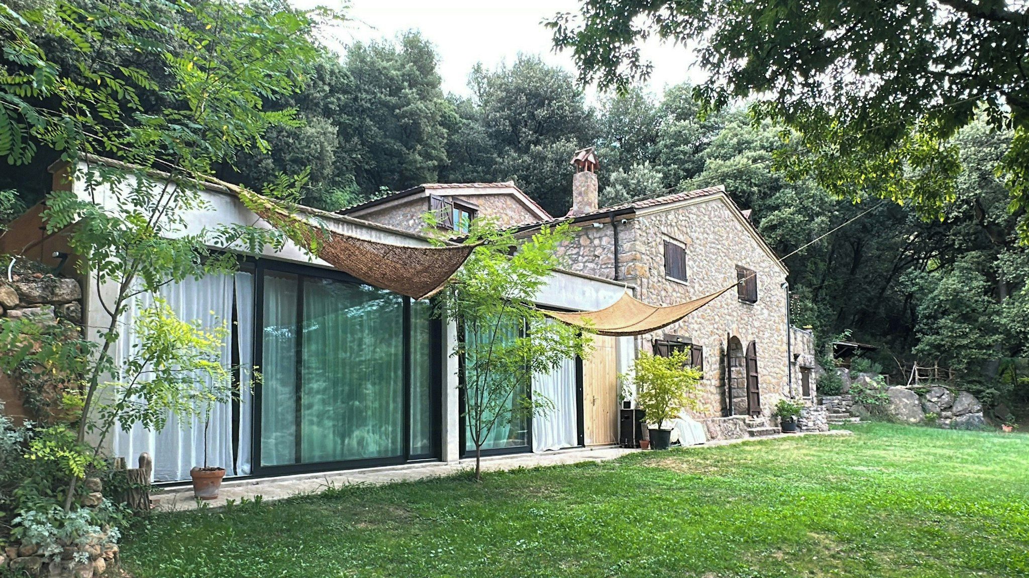 Una casa in pietra con un'ampia vetrata e un tetto in paglia.
