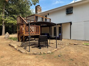 A house with a covered patio, outdoor furniture, and a stone chimney. - Chroma House: 3,000 sq. ft. 4BR Funky Art House w/Game Room-Sleeps 9 (Rogers)