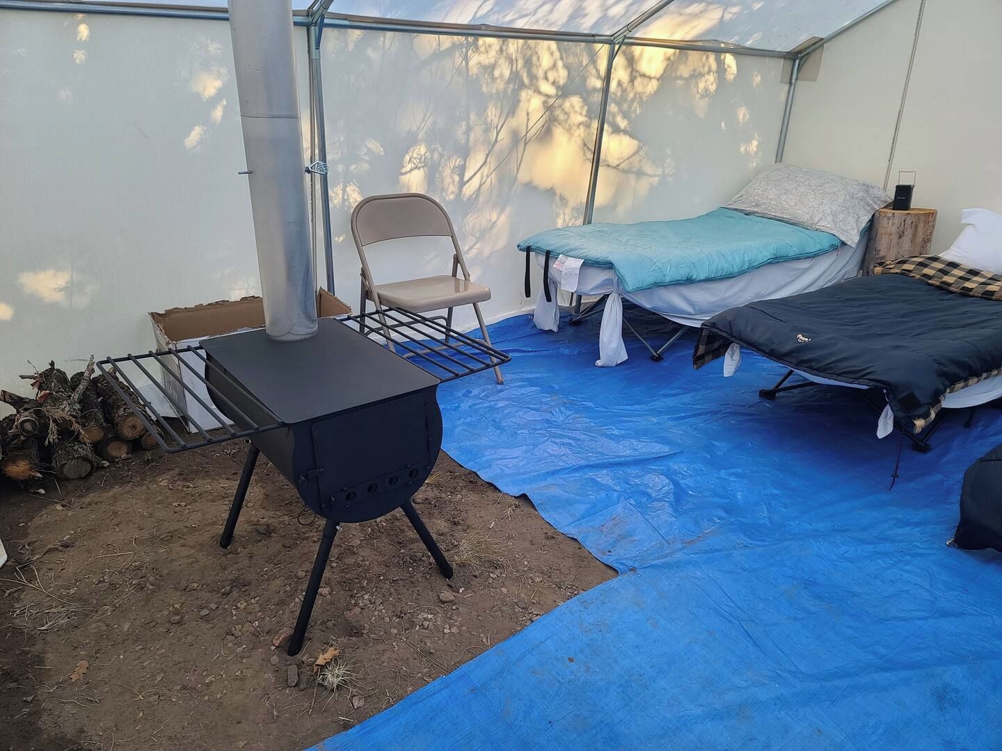 A tent with a bed, a chair, and a portable stove.