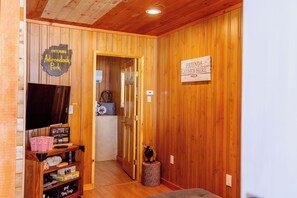 A wooden interior with a television, popcorn, and a sign indicating a gathering area.