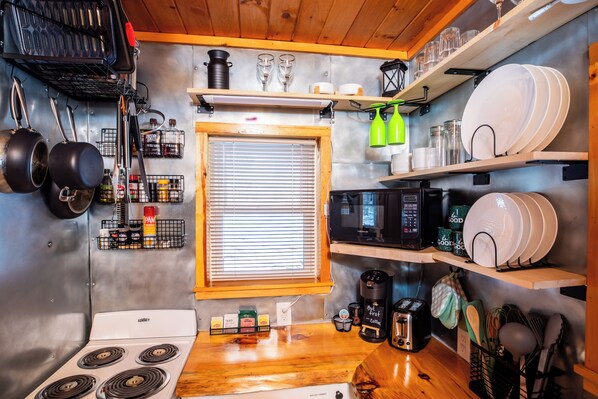 A compact kitchen with a stove, microwave, and various kitchen utensils.
