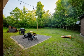 A backyard with a barbecue area, outdoor seating, and a ping pong table.