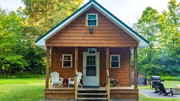 A small wooden cabin with a porch, two windows, and a door.