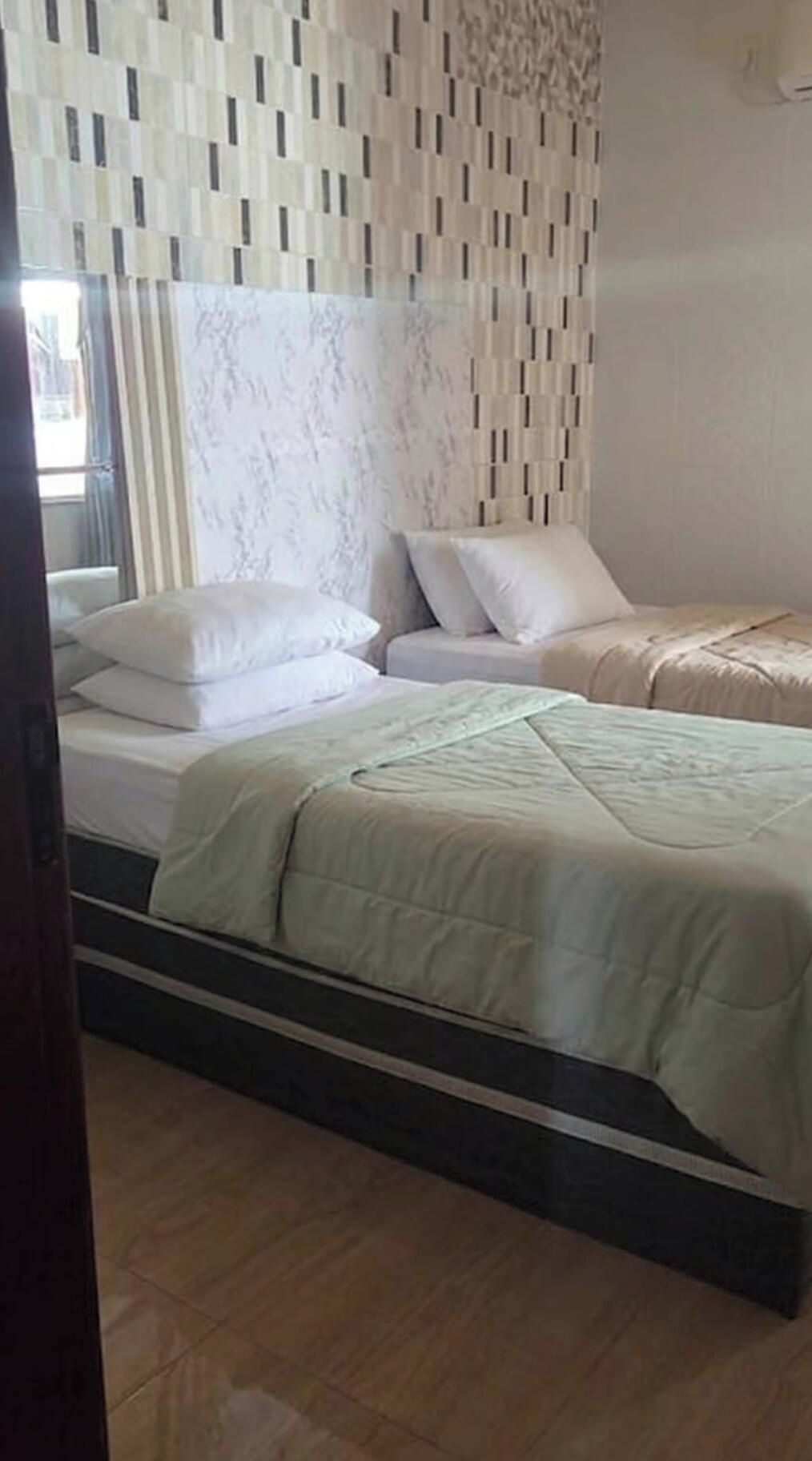 A bedroom with a bed, pillows, and a patterned wall.