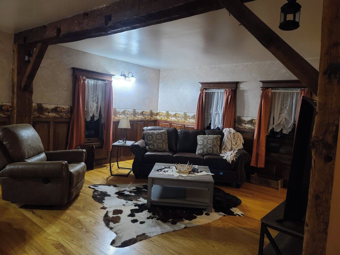 A cozy living room with a leather sofa, a wooden coffee table, and a cowhide rug.