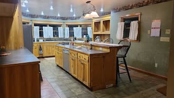 A kitchen with wooden cabinetry, a central island, and a dining area with chairs.