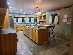A kitchen with wooden cabinetry, a central island, and a dining area with chairs.