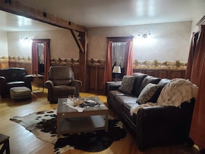 A living room with a leather sofa, a leather armchair, a coffee table, and a cowhide rug.