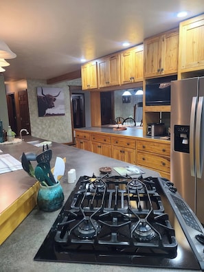 A kitchen with wooden cabinets, a stainless steel refrigerator, and a gas stove.
