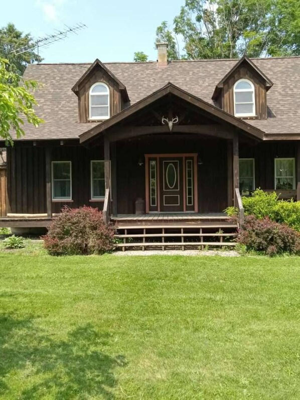 A two-story house with a front porch, a chimney, and a large window.