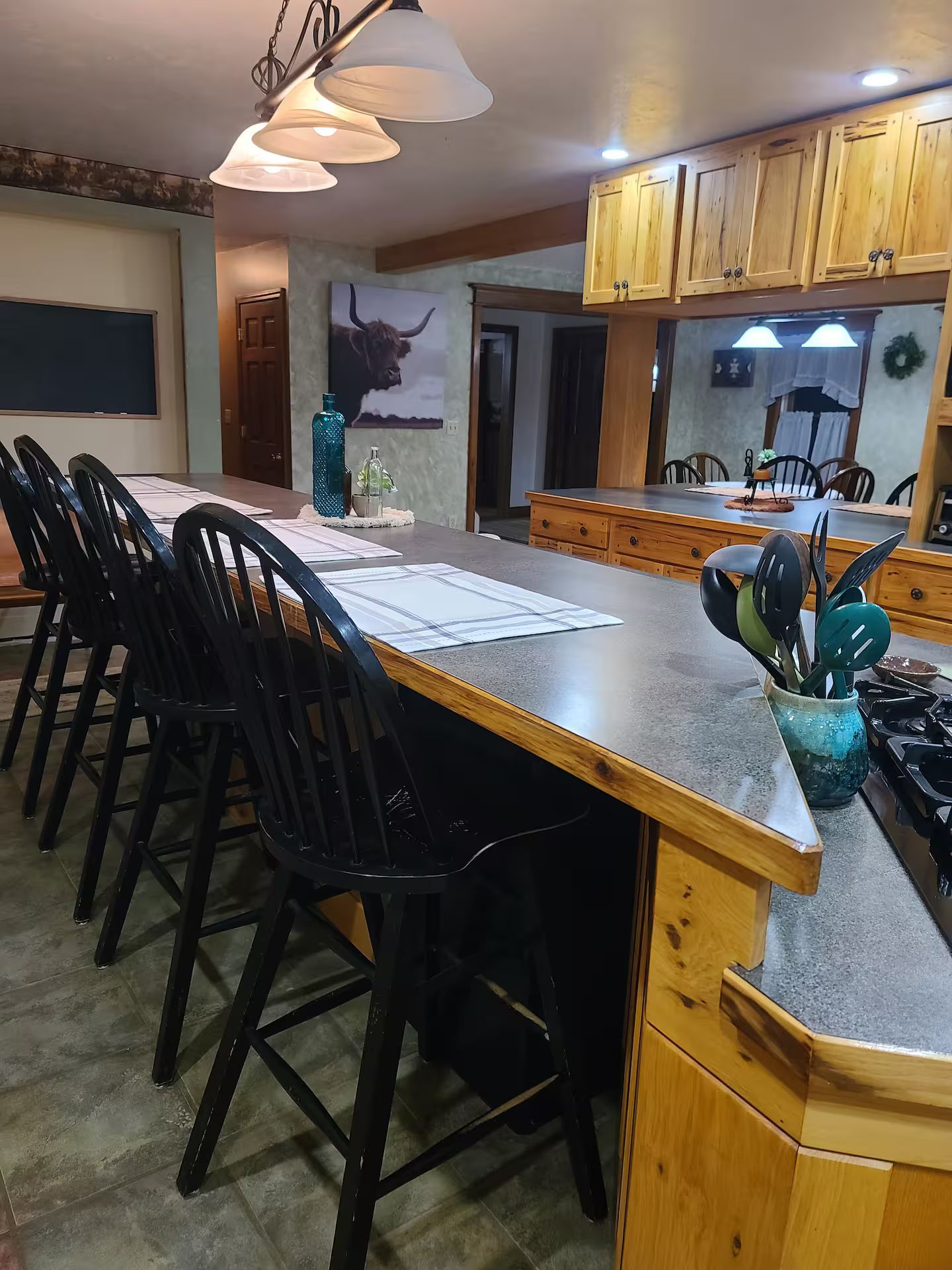 Une cuisine dotée d’un grand îlot central, de meubles en bois et de tabourets de bar.