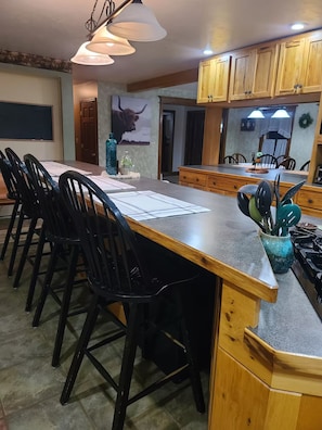 A kitchen with a long island, wooden cabinets, and bar stools.