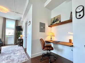 A modern office space with a desk, chair, lamp, and a clock on the wall. - DWTN New Haven | King Bed | Free Parking | Gym (New Haven)
