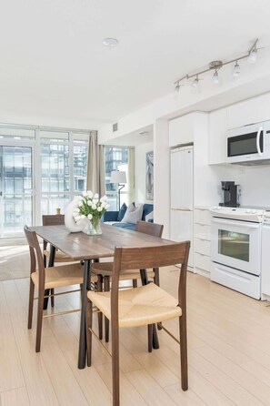 A modern kitchen with white cabinets, a microwave, and an oven. - Luxe Downtown Suite Steps to Entertainment District (Toronto)