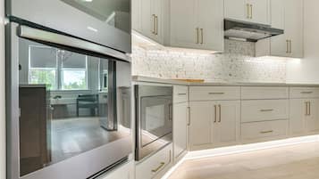 Une cuisine moderne dotée d’appareils électroménagers en acier inoxydable, de meubles blancs et d’un dosseret en carreaux hexagonaux.