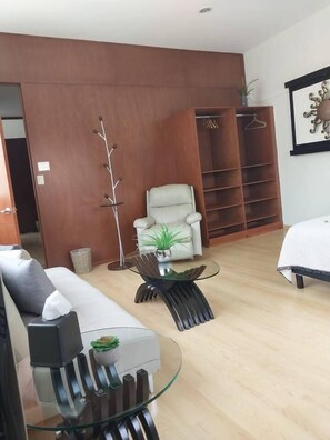 A modern living room with a sofa, a glass coffee table, a chair, a coat rack, and a wardrobe. - Private Pool House in Oaxaca (Oaxaca de Juárez)