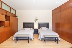 A bedroom with two beds, wooden wardrobes, and a bedside table with a lamp. - Private Pool House in Oaxaca (Oaxaca de Juárez)
