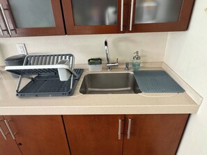 A kitchen with a sink, a dish rack, a soap dispenser, and a small trash bin. - Private Pool House in Oaxaca (Oaxaca de Juárez)