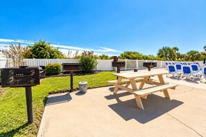 An outdoor patio area with a picnic table, barbecue grills, and lounge chairs. - Beachfront Condo w/ Pool & Noon Check-In (Myrtle Beach)
