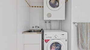 A laundry area with a washing machine, a sink, and a towel rack. - Ocean Plaza 115 - Coolangatta Beachfront - Linen Provided - Min. 3 Night Stays (Coolangatta)