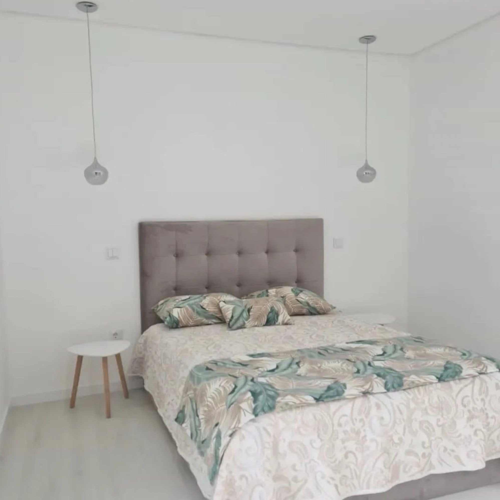 A bedroom with a bed, a nightstand, and two pendant lights.