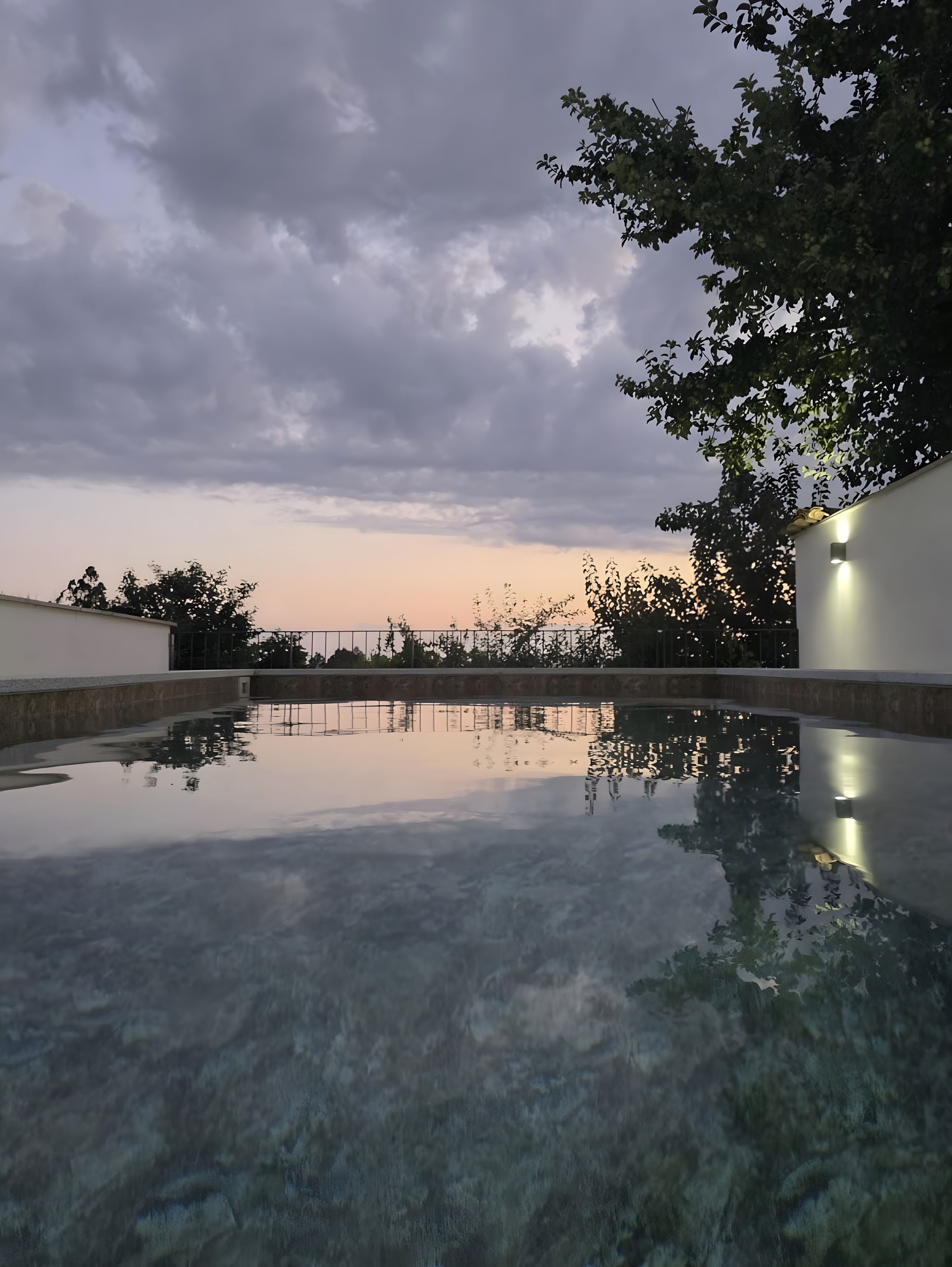 A clear swimming pool with a view of the sky and trees.