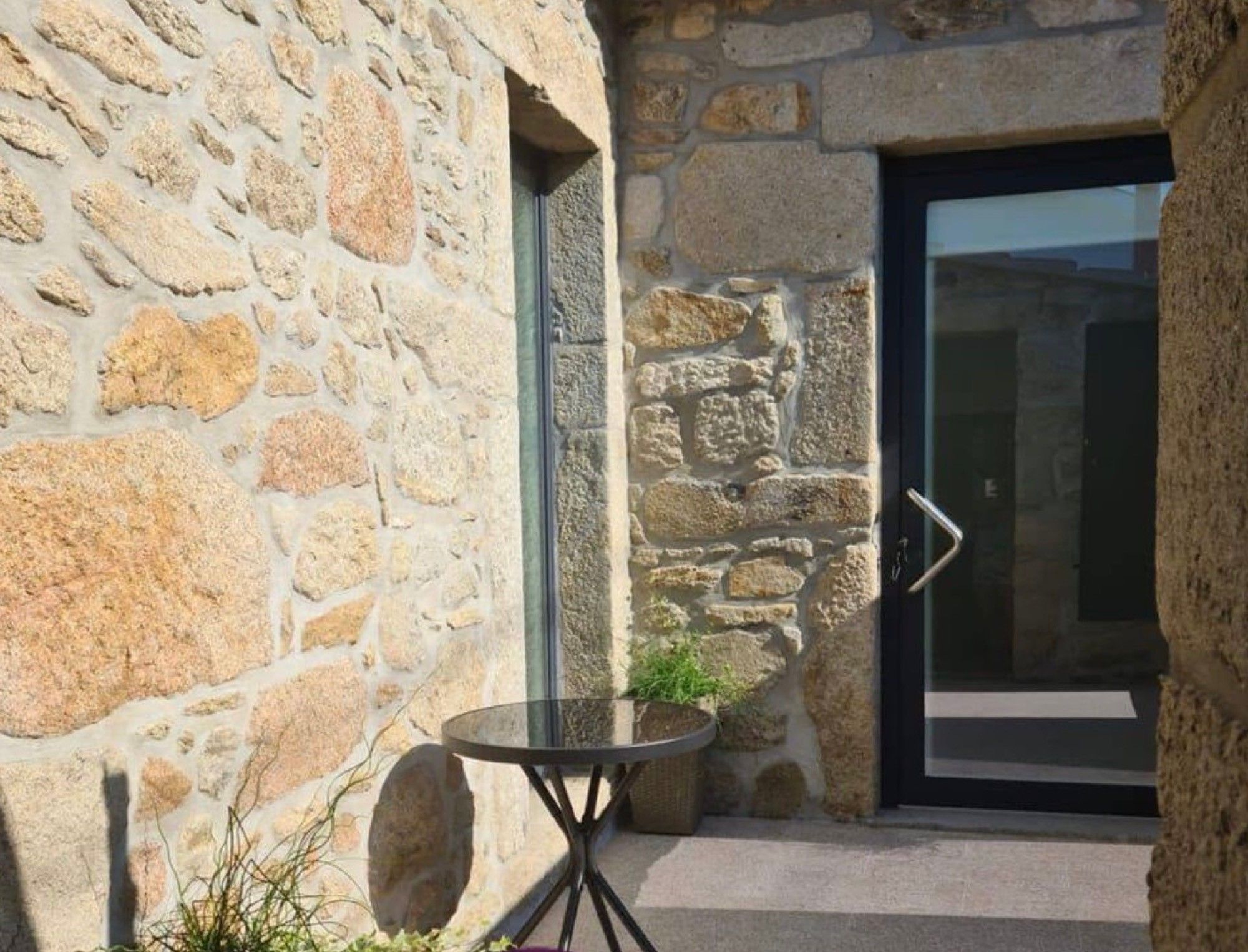 A stone building with a glass door and a small table with chairs outside.