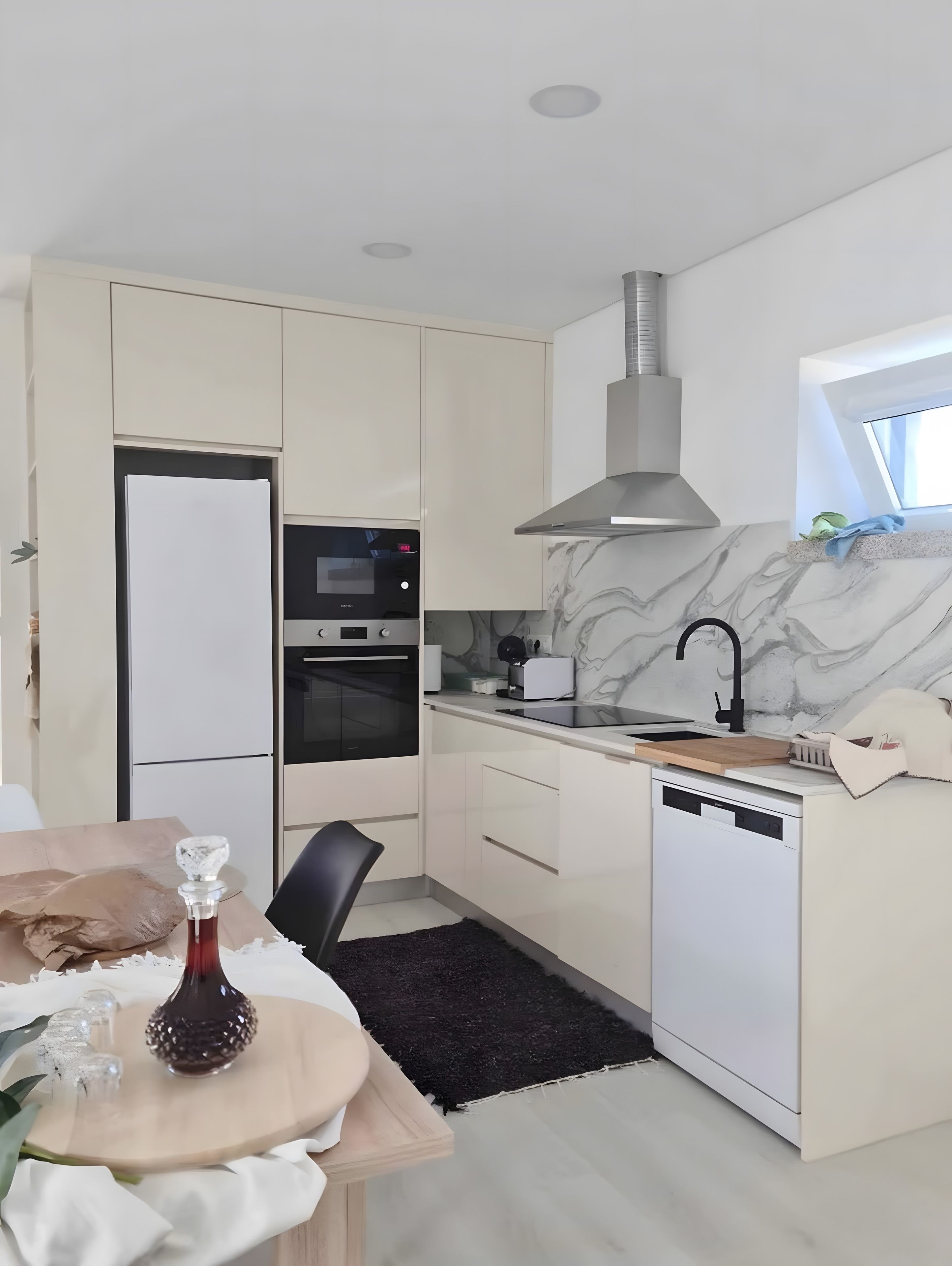A modern kitchen with built-in appliances, a marble backsplash, and a window providing natural light.