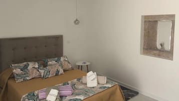 Une chambre à coucher avec un lit, une table de chevet, une lampe suspendue et un miroir au mur.