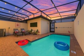 An indoor swimming pool with a glass ceiling, lounge chairs, and a flamingo decoration. - 5BR Townhome Near Disney Pool, by Clubhouse (Kissimmee)