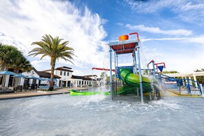 A water park with a water slide, a pool, and palm trees. - 5BR Townhome Near Disney Pool, by Clubhouse (Kissimmee)