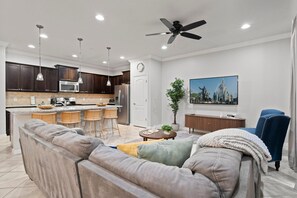 A modern kitchen with dark wood cabinets, stainless steel appliances, and a bar area with stools. - 5BR Townhome Near Disney Pool, by Clubhouse (Kissimmee)
