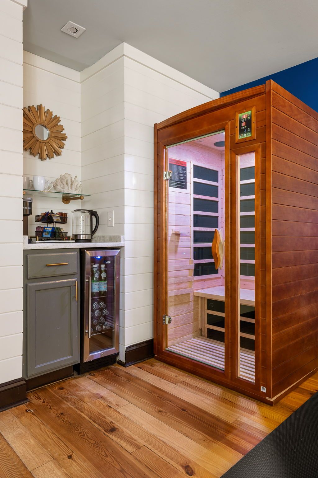 Una habitación con sauna, cafetera y un mueble pequeño.
