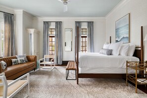 Quarto de hotel com cama, sofá, banco e cadeira.