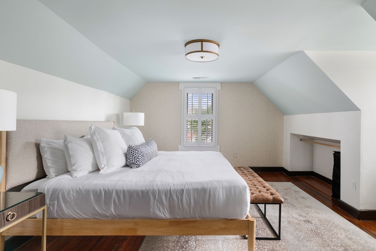 Quarto com cama, luminárias de cabeceira, janela e luminária de teto.