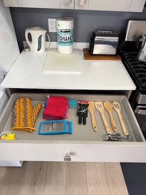 A kitchen with a white countertop, a kettle, a roll of paper towels, and a drawer containing kitchen utensils. - Relaxing Luxury Villa Private Beach Pool AC WiFi (Turtle Bay)