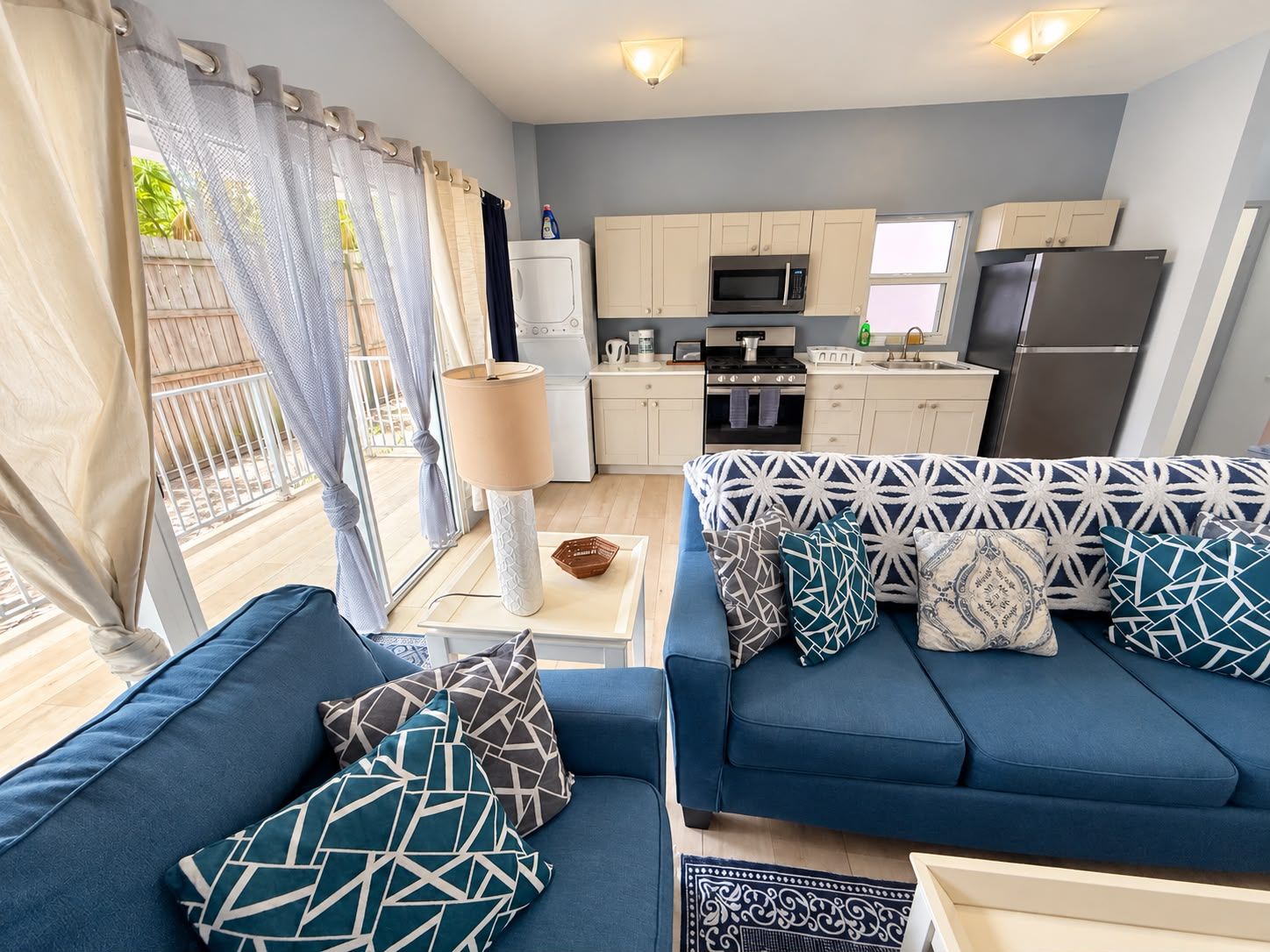 A modern living room with a sofa set, a dining table, and a kitchen area with appliances.