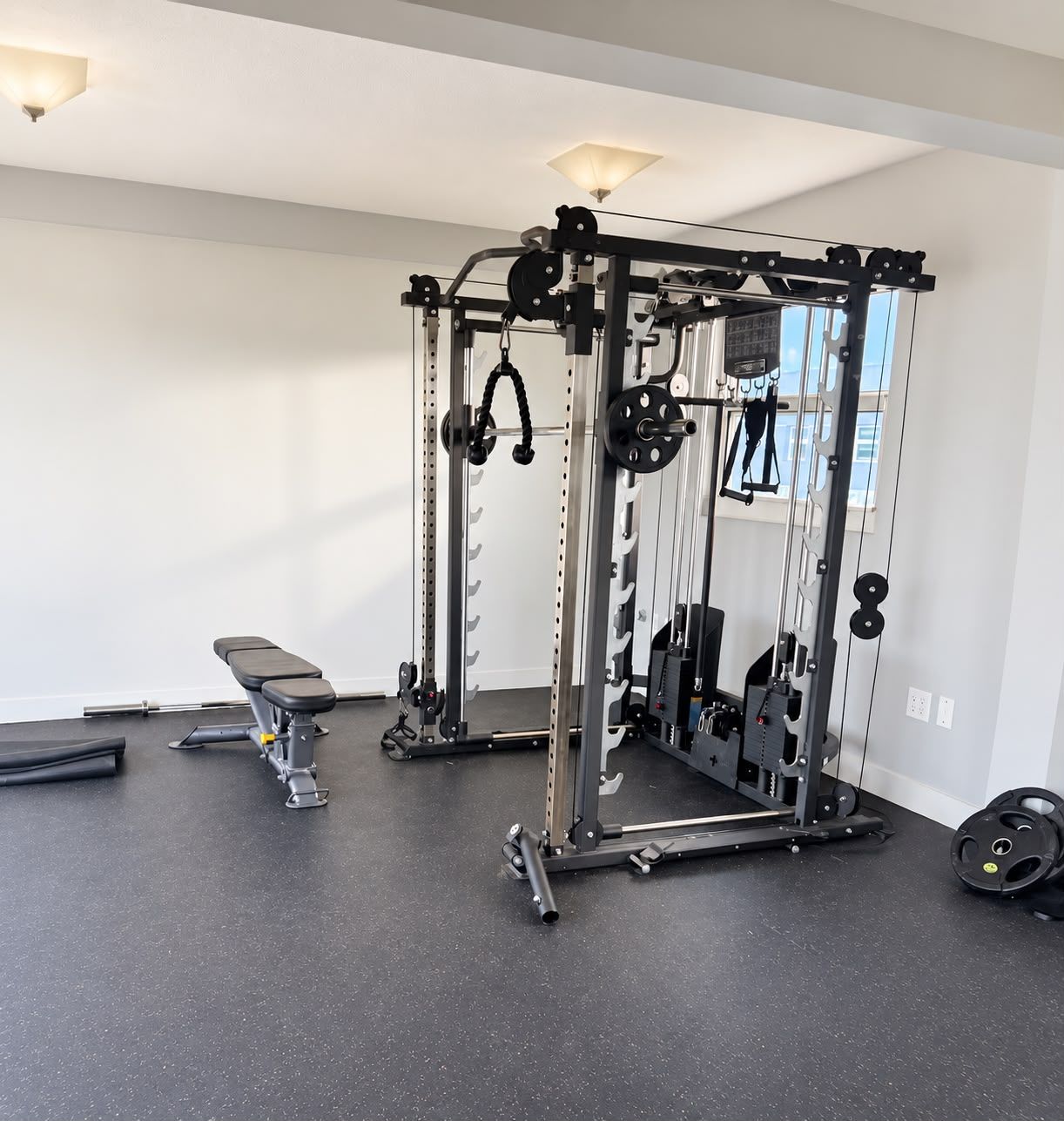 A gym with a squat rack, bench, and various weight plates.