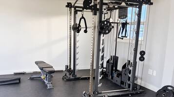 A gym with a squat rack, bench, and various weight plates.