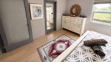 A room with a door, a dresser, a mirror, a rug, and a window.