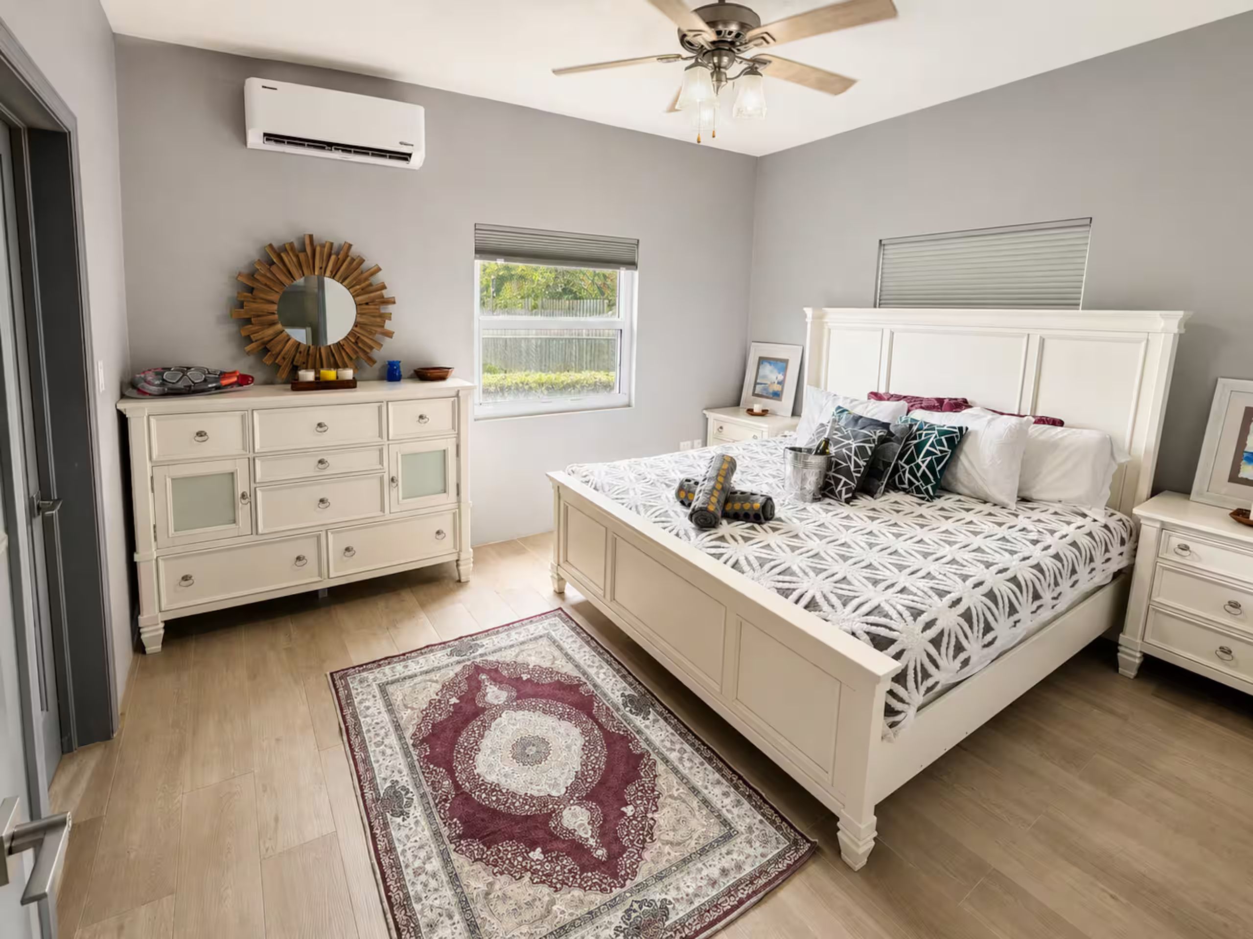 Ein Schlafzimmer mit Bett, Kommode, Schminktisch und Deckenventilator.